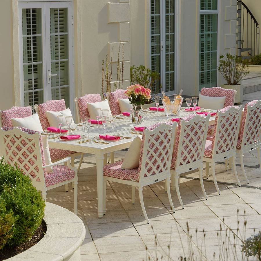 Dekket langbord med hvite Oxley's hagemøbler og rosa puter på en terrasse